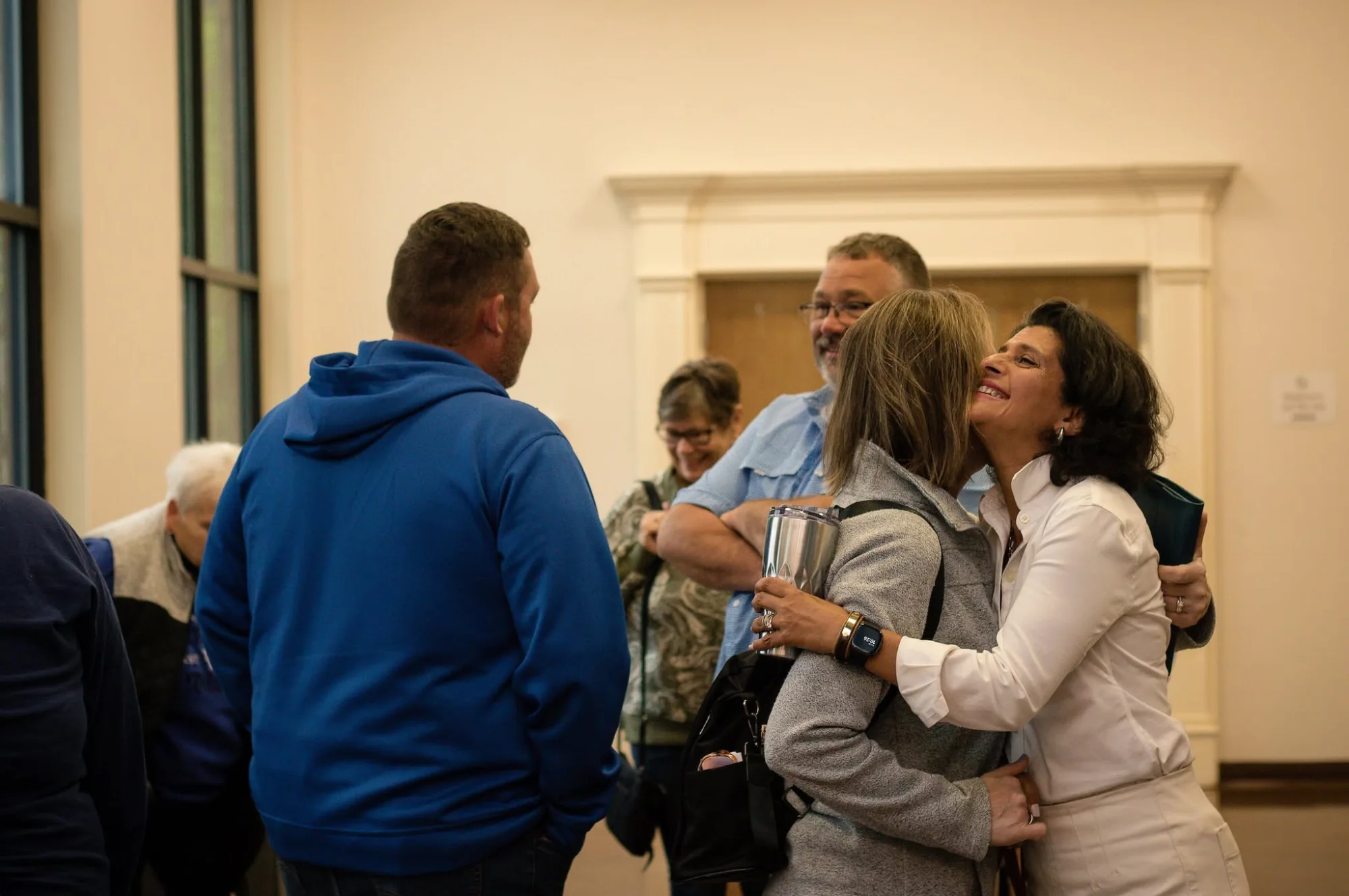Two women embrace warmly at a Celebrate Recovery gathering, representing community support