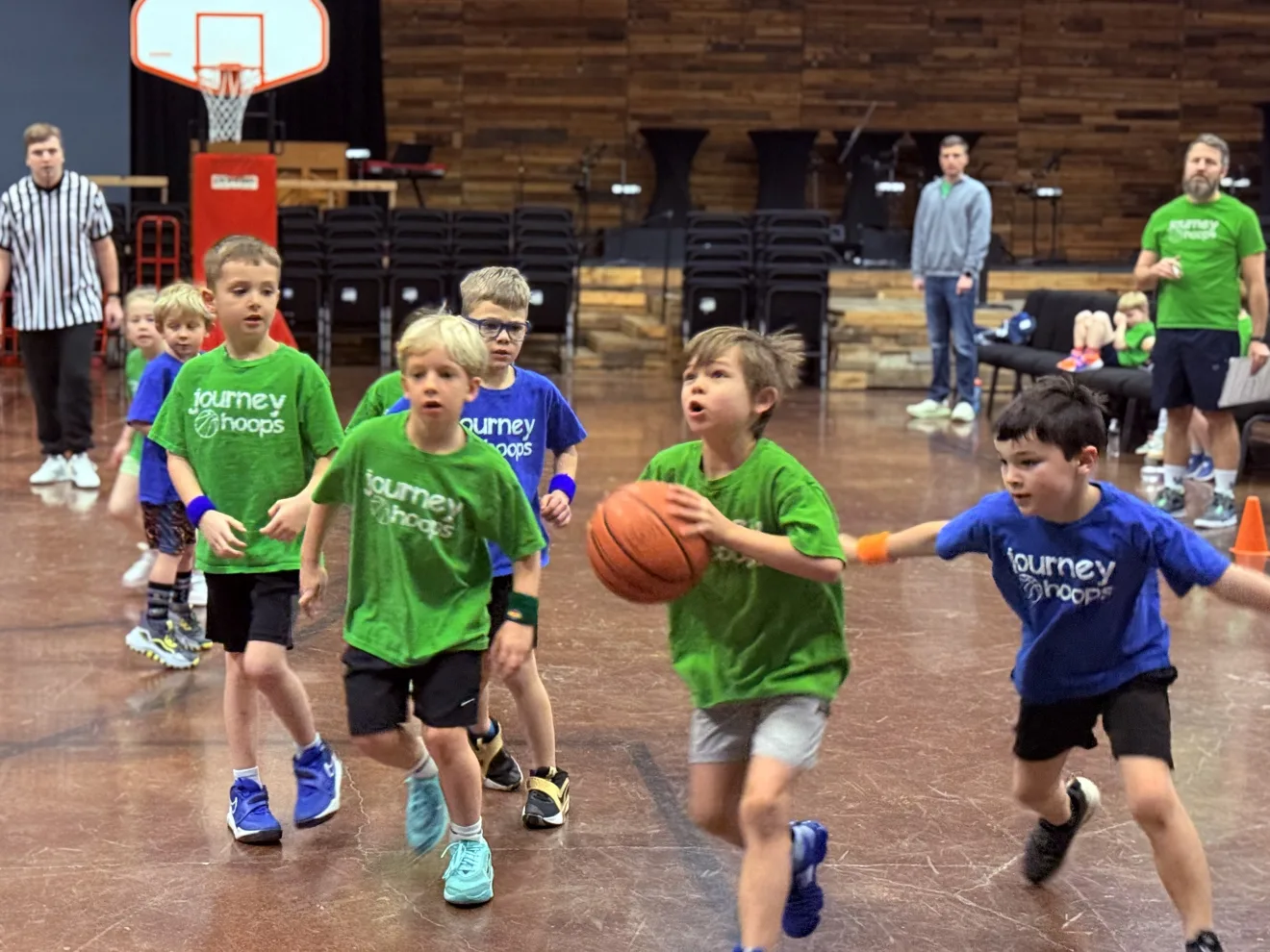 Kids in green and blue Journey Hoops jerseys run down the court during a basketball game at Journey Church.