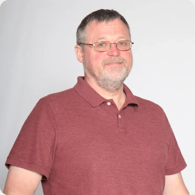 David Iglehart, Facilities Manager at Journey Church, smiling in a maroon polo shirt and glasses.