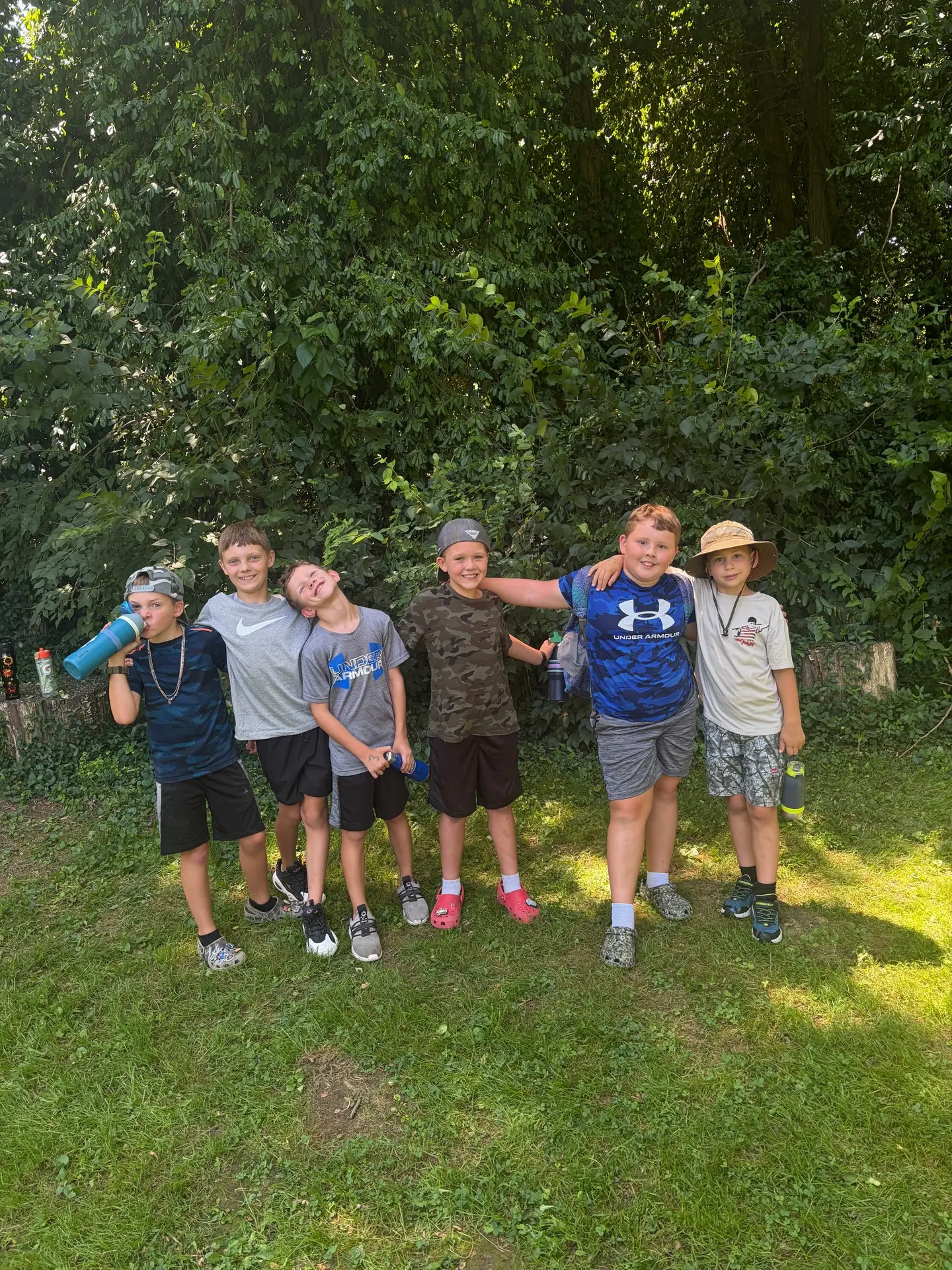 A group of boys posing together at the edge of the woods during a camp hike