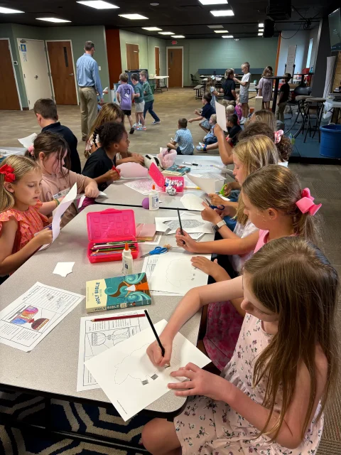Children work on a craft project at tables in the Journey Church lobby while families gather nearby.