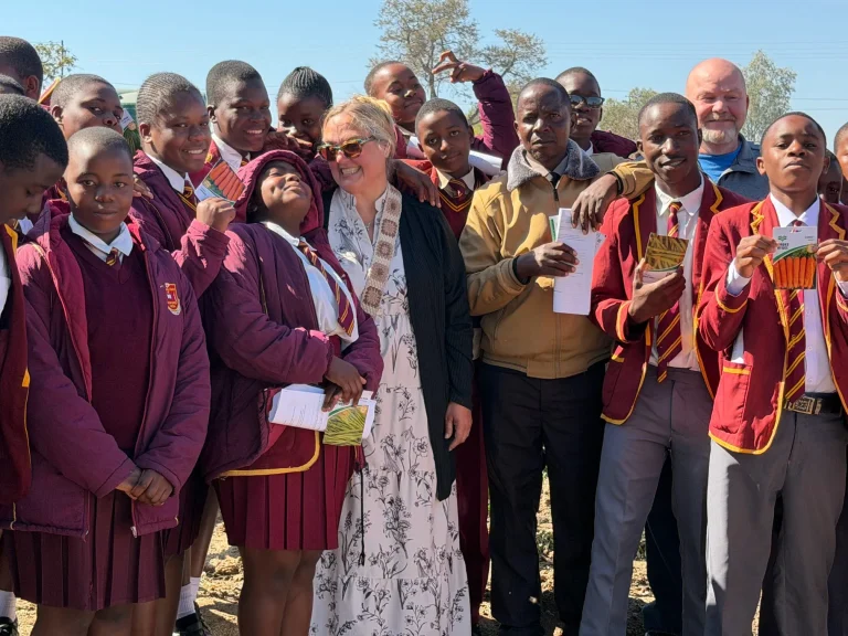 A Journey Church mission team member poses with students in maroon school uniforms at Hippo Valley Christian Mission in Zimbabwe.
