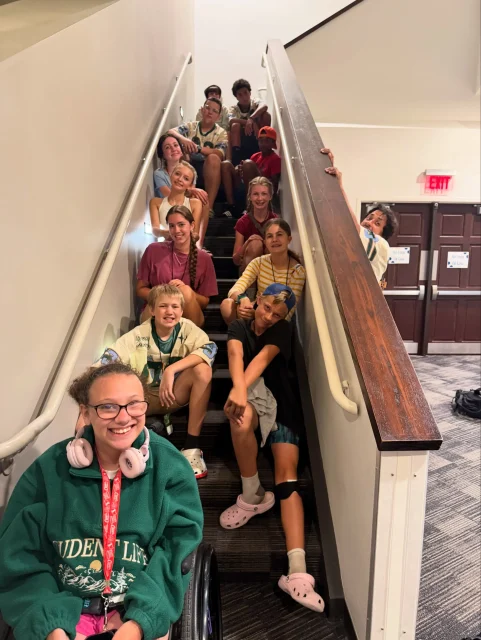 Students sitting together on a stairwell smiling at the camera