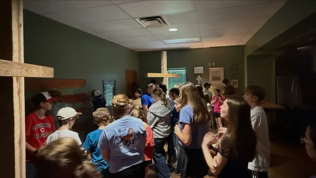 Students standing and talking together in a room decorated with wooden crosses
