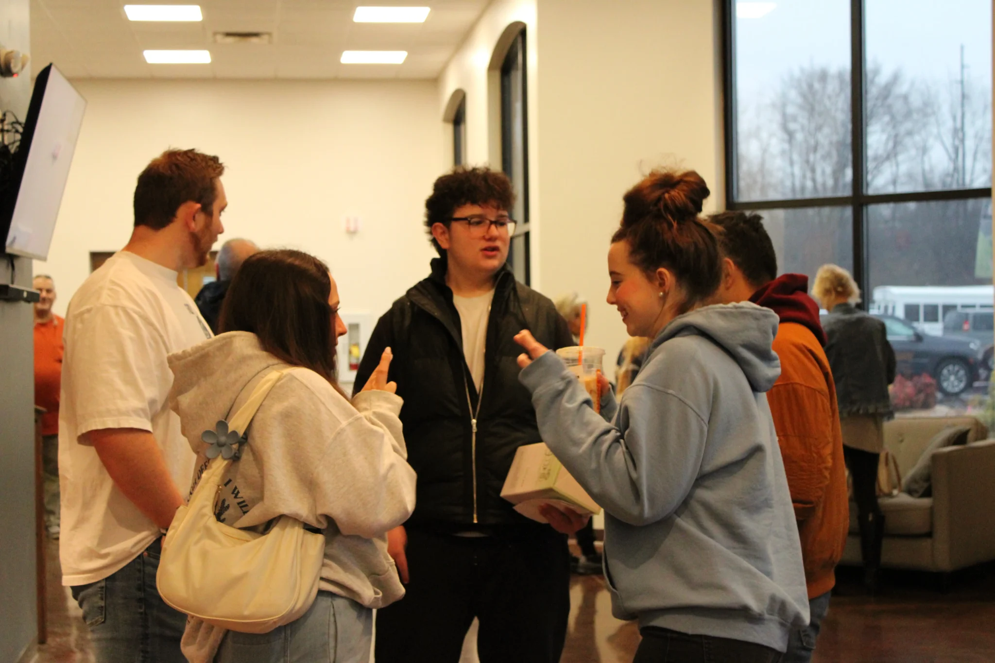Students standing and talking together in a bright gathering space before a student service
