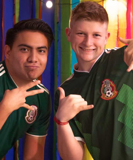 Two Journey students wearing Mexico national team soccer jerseys smile and pose together, representing the 2027 Mexico City mission trip.