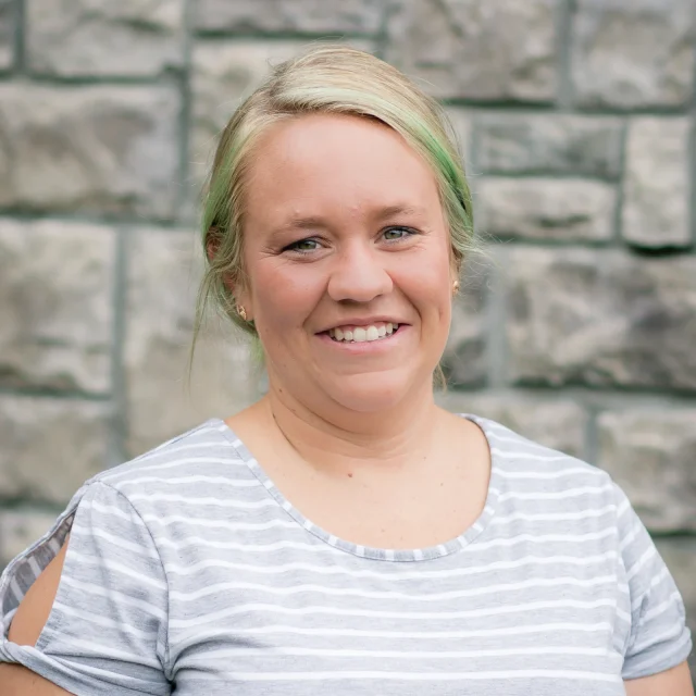 Adriane Routt, Classroom Aide at Journey Preschool, smiling in a gray and white striped top.