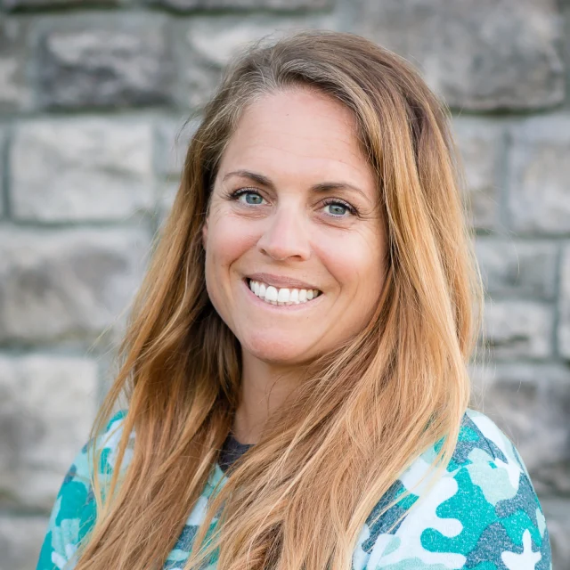 Brynn Deaton, Preschool Teacher at Journey Preschool, smiling in a teal floral top with long blonde hair.
